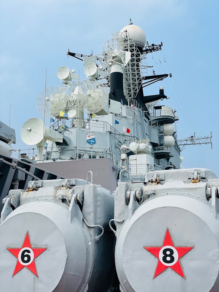 Close-up of a military vessel with satellite dishes under a clear blue sky.